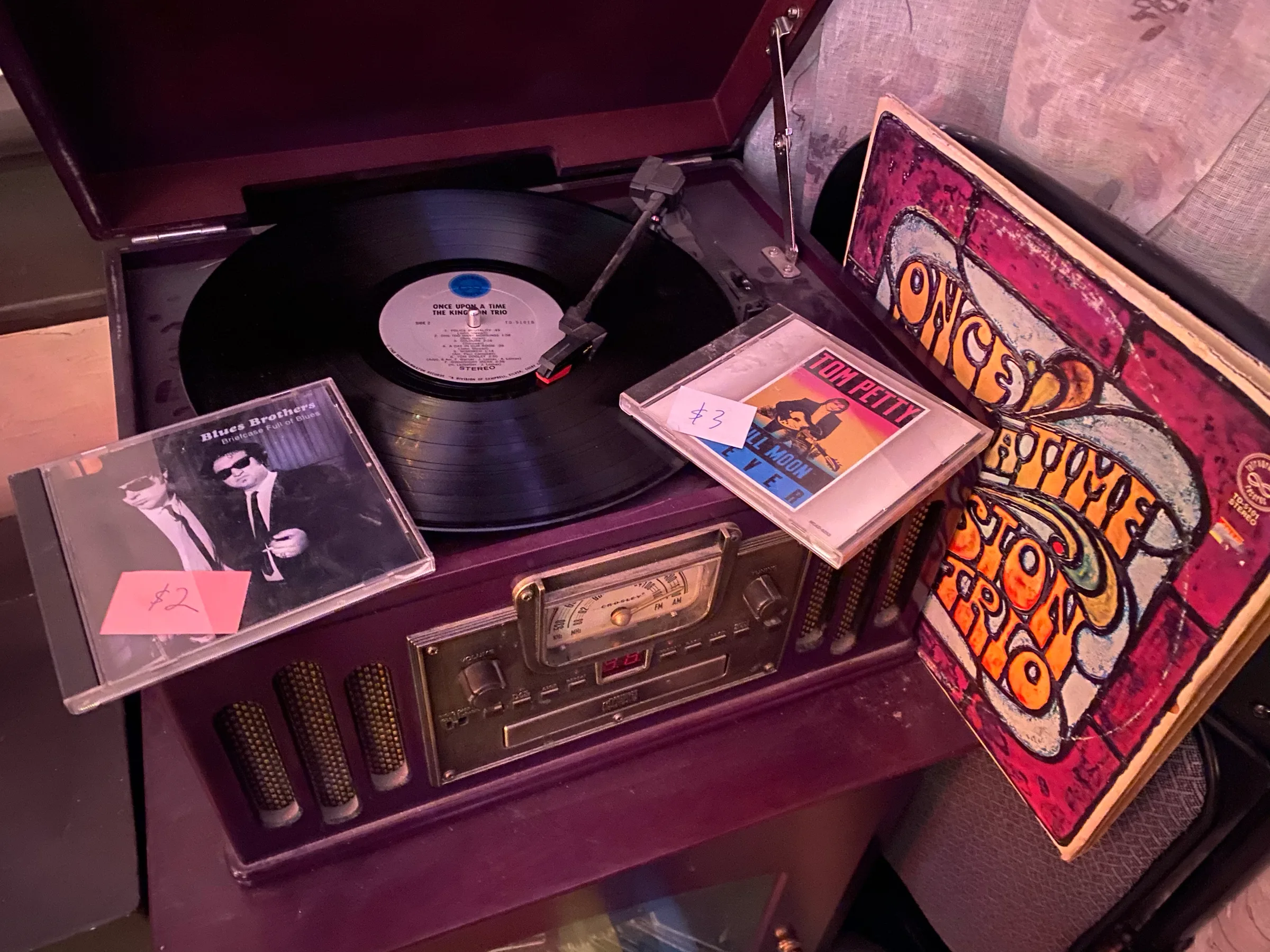A picture of a crossly record player with two CD's on top one the Blues Brother Briefcase full of blues, the other Tom Petty Full Moon Fever, and a record to the side of the Kingston Trio. Merry Christmas to me and unexpected trip to unexpected trip to Algonquin Records 